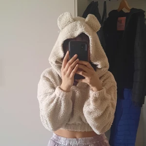 Mjukiströja med öron - Gullig tröja med öron på huvan. Croppad med resår vid midjan och armen. Beige/vit i färgen. På sista bilden syns hur utsida och insida ser ut. Pris kan diskuteras.