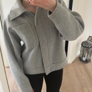 Grå vårjacka/kappa - Jättefin grå jacka som passar perfekt nu till våren. Jackan är i jättebra skick och nästan aldrig använd. Skriv gärna vid frågor eller för fler bilder!