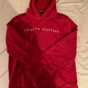 Röd Tommy Hilfiger hoodie i hyfsat bra skick, den har dock ett litet hål på den högra armen men det är ej något man tänker på.