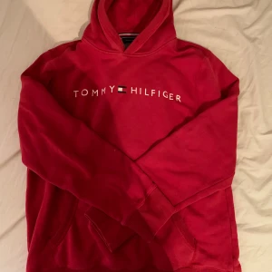 Tommy Hilfiger - Röd Tommy Hilfiger hoodie i hyfsat bra skick, den har dock ett litet hål på den högra armen men det är ej något man tänker på.