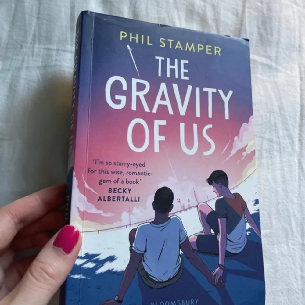 The gravity of us av Phil Stamper på engelska. Dennas framsida är något böjt i överkanten. . Böcker.