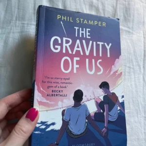 The gravity of us - The gravity of us av Phil Stamper på engelska. Dennas framsida är något böjt i överkanten. 