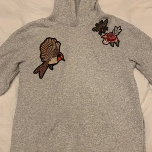 Grå Tjock Tröja med på sydda detaljer  - Snygg och lite oversized tjock tröja i grå med på sydda detaljer. Lite sliten men inget större slitag än vad man kan vänta sig. Kan skicka bilder med hoodien på om de skulle behövas! 💕priset kan diskuteras men är högre på grund av frakt