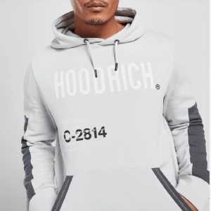  grå hoodrich hoodie - Hoodien är köpt från JD sports sen ett år tillbaka men har inte kommit till användning. Den har 3 ganska små hål på armen. Köpt för 850kr och säljs för 450kr men kan gå lite mer ner i pris!