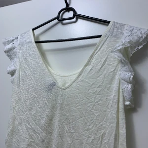 Topp - Topp med volangarmar i spetsmaterial, fint skick. Lite genomskinlig. Behöver strykas 🌸