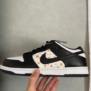 Supreme Nike SB Dunk Low "Stars" - Supreme x Nike SB Dunk lows "Stars" i svart färg, helt nya/oanvända och kvitto finns!  Storlek EU 45 / US 11  Fraktkostnad: 99kr i hela landet!
