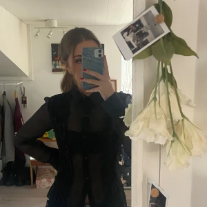 Svart volang skjorta - Svart volang skjorta från Surya Internationalz. Står ingen storlek men passar XS/S