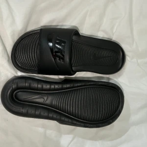 Svarta Nike tofflor - Helt oanvända och är i storlek 38. Säljs pga dem är för små!