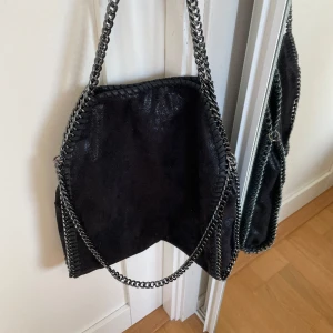 Snygg StellaMcCartney liknande väska! - Snygg väska i ett svart glittrigt material med silverkejdor. Liknar de populära Stella McCartney väskorna. Materialet på insidan är mönstrat men det är inget man märker av. Skriv för fler bilder eller frågor! 