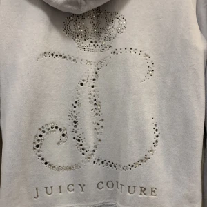 Vintage Juicy Couture  - Ljusblå Vintage Juicy Couture hoodie i storlek M. Passar på mig som vanligtvis har storlek XS och är 158cm lång. Tröjan är i bra skick förövrigt men trycket är skadat. Hälften av stenarna på ryggen har ramlat av. OBS ENDAST SWISH💞