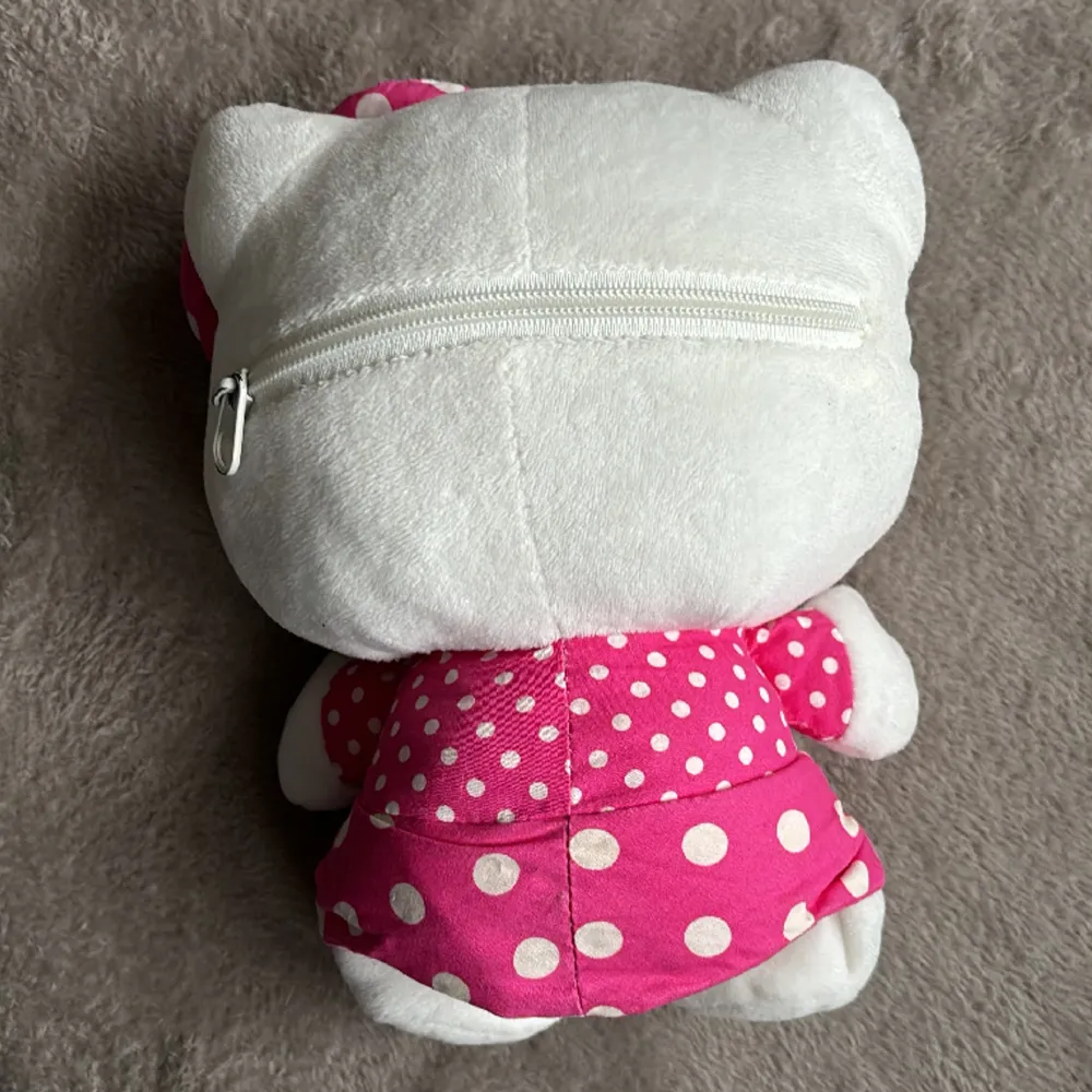 Söt Hello Kitty-väska utan axelrem och handtag. Dragkedja på baksidan, man får endast rum med något litet, se bild. Ca 25 cm hög. Fint skick. Väskor.