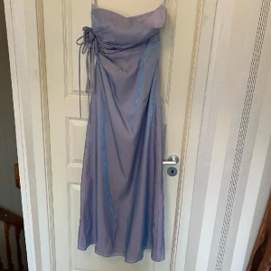 Klänning - Strapless klänning, skimmrande i färgen.