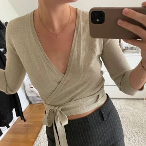Glittrig omlotttopp - En superfin glittrig omlotttopp från Ilse Jacobsen. Använd vid ett tillfälle så är i mycket fint skick. Trekvartsärmar och knytning runt magen, lite kortare i modellen💛🧡
