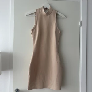 Klänning - Jättefin beige klänning med en öppenrygg från Nelly trend. Knappt använd
