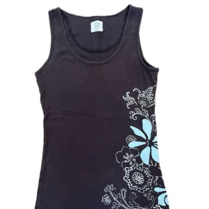 Linne Med Tryck - Jättefint linne med tryck av blommor med detaljer o mönster. Den är vintage men i bra skick. Tröjan ser svart ut men på nära håll är den mörkbrun. Skriv gärna för att se mer bilder eller om ni har några frågor! Skriv också innan ni använder ’köp nu’🤍