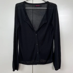 Svart blus / cardigan med knappar - En svart blus/cardigan i smånätigt/meshigt tyg 🖤Jättefin att ha över linnen eller andra tröjor! Har en liten defekt på baksidan av ena axeln, se bild 4. Stl L men skulle säga att den snarare är M och passar lite oversized på mindre storlekar 