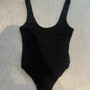 Vanlig svart body tröja från Bikbok med öppen rygg och knappar nertill. Använd en gång. 