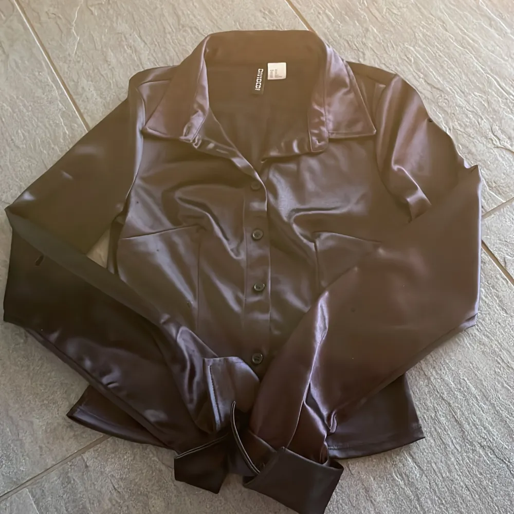 En svart glansig skjorta från divided H&M. Den är i storlek xs. Säljer den för att inte kommer till användning och använd fåtal gånger, inga defekter! Frakten kostar 58kr!💕. Skjortor.
