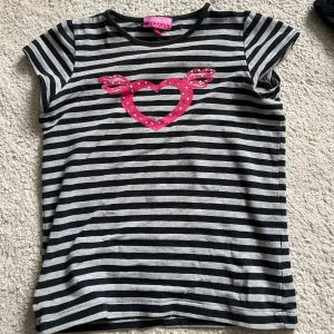 Baby tee  - Så himla cool baby tee!! Jag är vanligtvis en ca/s och den passar på mig. Hjärta med vingar som har rhinestones i mitten. Bra kvalitet!