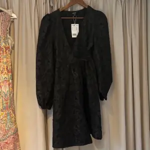 En svart puffig klänning från Monki som är helt ny & aldrig använd, med prislappen kvar, nypris: 500 kr. Storlek Xs. Har ett blommigt mönster som man ser på bilderna. 