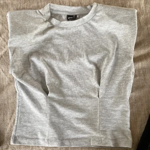 Grå Gina topp - Säljer denna gråa toppen från Gina tricot då den inte kommer till användning. Den är i storlek xxs med passar som xs, den är coolt. Knappt använd så i mycket bra skick! 💓💓