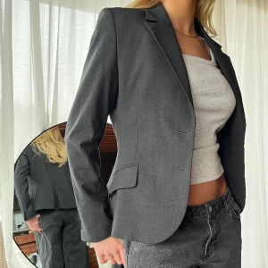 Kavaj - Grå kavaj med en kortare passform. Fraktkostnad tillkommer. 