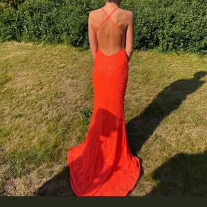 Min balklänning från 2023!   Paljettklänning i neon orange färg. Öppen i ryggen med korsade band liknande till ett X. Längre släp baktill.  Säljer då jag inte kommer använda den igen.