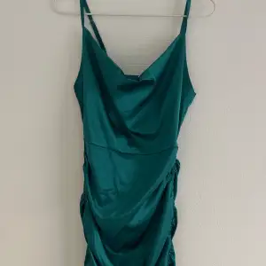 Grön kort satin klänning som aldrig använts, i storlek xs men man kan ändra längden lite hur man vill med snörena vid sidorna🫶🏼 Den har ett jättefint fall i uringningen och passar toppen till fest💚