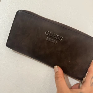 Guess plånbok - Den är i bra skick. Det är repor på metallbiten under texten guess framtill. 