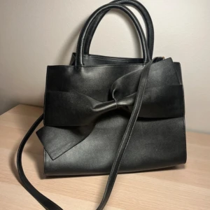 Väska - Fake läder väska från Oriflame Stockholm. Har en lång axelrem och handbag handtag.