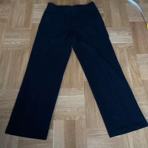 Cos kostymbyxor  - Svarta Ull-kostymbyxor i storlek 46, notera dock att materialet inte är som vanliga kostymbyxor utan att de är nästan som att de är stickade. Fläck på rumpan från limm tror jag.   Innerbenslängd: 75cm   Fotöppningen: 24cm   Total längd: 103cm   Midja