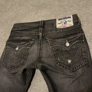 750 - Sjukt feta True Religion Jeans. Galen wash i en mörk grå färg. Lite uppsydda av den tidigare ägaren samt att sömmarna är uppsprättade lite grann för en flare. Straight fit. Längd: 100,5 cm