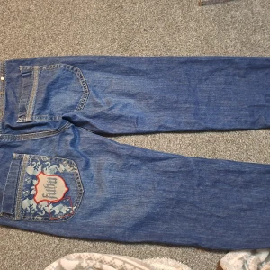 Snygga Fubu jeans - Snygga jeans med tryck! Är väldig snygga men lite för små för mig. Måtten är: midjan:39cm Insim:66 längd:87cm