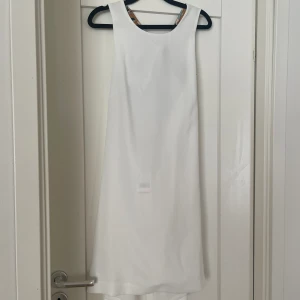 Vit klänning - Helt ny/oanvänd klänning från Mango. Storlek L men M kan också ha den. Fräsch och fin till sommaren eller student. Man skapar sin egna roset bakom.