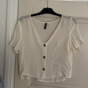 Vit blus  - Säljer denna krämvita blusen som är superfin ni till våren och sommaren. Köpt på hm och är nästa oanvänd. Materialet har en väldigt fin struktur och bruna knappar. Storlek 36.💞 Hör av er vid frågor eller mer bilder.☺️