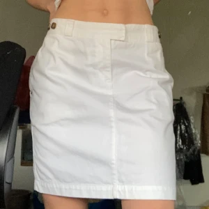 Tommy Hilfiger Kjol - Super snygg vit Tommy Hilfiger jeans kjol med fina detaljer. Cool baksida och färgglada blommönster på insidan av kjolen. Säljs inte längre då det var en av deras limited edition kollektion. Använd 1 gång så Nyttskick!💝