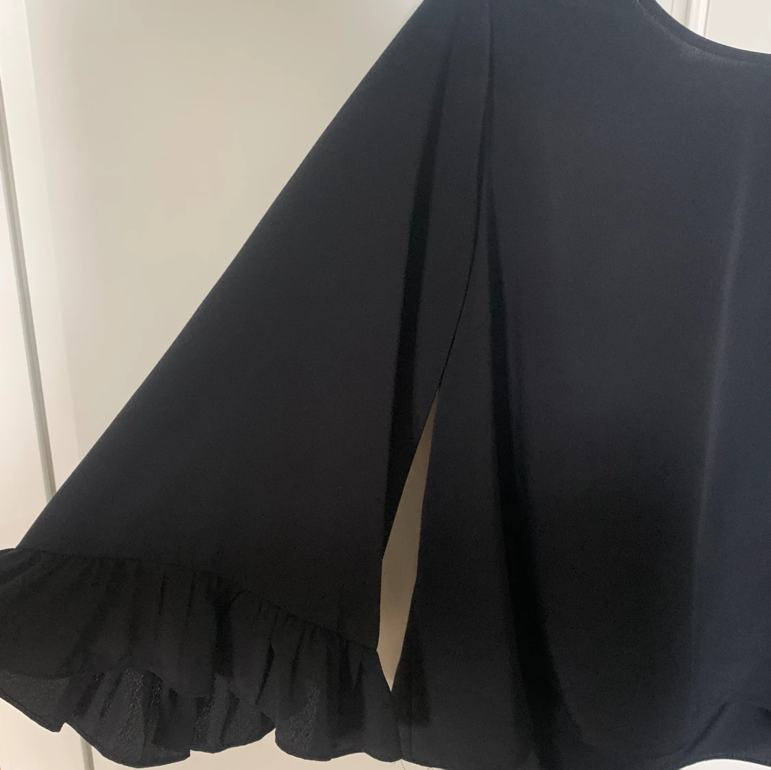 Svart blus med vida Ă€rmarđ