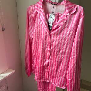Rosa pyjamassett med Victoria secret liknade mönster. Innehåller en långärmad skjorta, långa pyjamasbyxor, pyjamasshorts,matchande sovmask, scrunchie och förvaringspåse. Aldrig använd och prislapp kvar.
