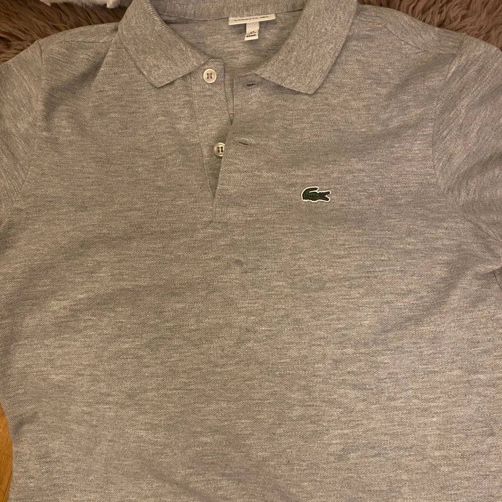 Säljer Lacoste piké grå t shirt. Har bara  prova på den. Storlek XS helt ny har paketet och allting. Säljer pgv för liten. . T-shirts.