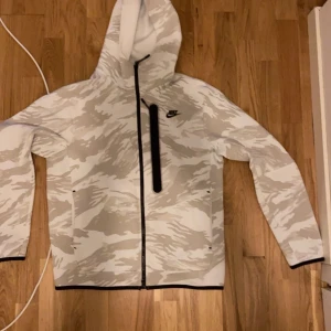 Vit camouflage Nike Tech - Tröjan är i toppen skick och har knappt används, tröjan är bra för dig som inte söker en så tjock tröja men som är skön till dem svalna sommarkvällarna, denna modellen är också väldigt svår att få tag i eftersom den är slutsåld helt i butiker.