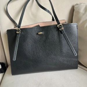 Väska  - En handväska i stadig läderimitation. Insida i kontrastfärgad mockaimitation. Tre stora innerfack. Guldfärgade detaljer. Storlek 14,5x24x35 cm