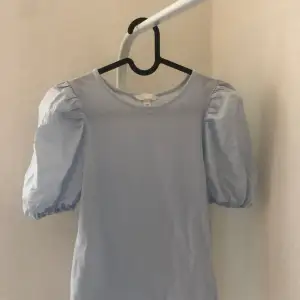 Snygg babyblå tshirt med puffärmar. Köptes på H&M i somras och anvönd cirka 1 gång. Bra skick.