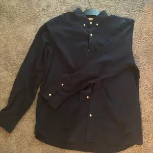 Mörkblå skjorta som bara använts en gång, då den tyvärr va för stor. Den är i tunnt material och passar perfekt till sommaren. Skick 9,5/10