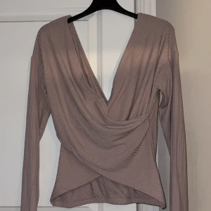 Gammel/smutsrosa tröja  - En gammel/smutsrosa tröja som slutar vid naveln. Halv öppen i ryggen och vid brösten/v-ringad med en typ av volang vid magen. Knappt använd så i bra skick! 