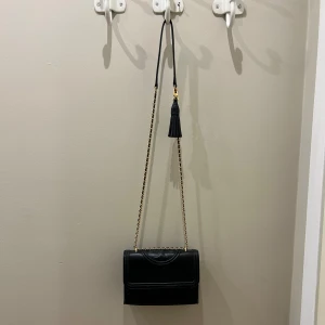 Tory burch väska  - Svart väska från tory burch som går att justera längden på. Väskan stängs med en magnet. I använt skick