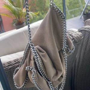 Stella McCartney  - En beige äkta stella McCartney! Säljer pga att jag har tröttnat! Väskan har slitage på kedjan och 2 pyttesmå hål som inte syns, därav priset. Hör av er vid föera frågor eller bilder!
