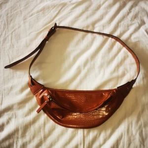 Snygg magväska!  - Riktigt snygg orange-brun magväska med justerbar rem och guldiga detaljer, som nyskick då den nästan aldrig varit använd. Den är krokodilmönstrad och har flera fack vilket är mycket praktiskt. Skriv för mer info💓