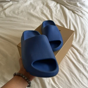 Yeezy Slide Azure - Säljer mina använda Yeezy Slides i gott skick! De är väldigt sällan använda, skulle säga att de är 9/10. Endast undersidan smutsiga. Fraktar med dubbelbox. Kvitto finns från CONFIRMED appen. Bara att höra av sig vid frågor 🐳