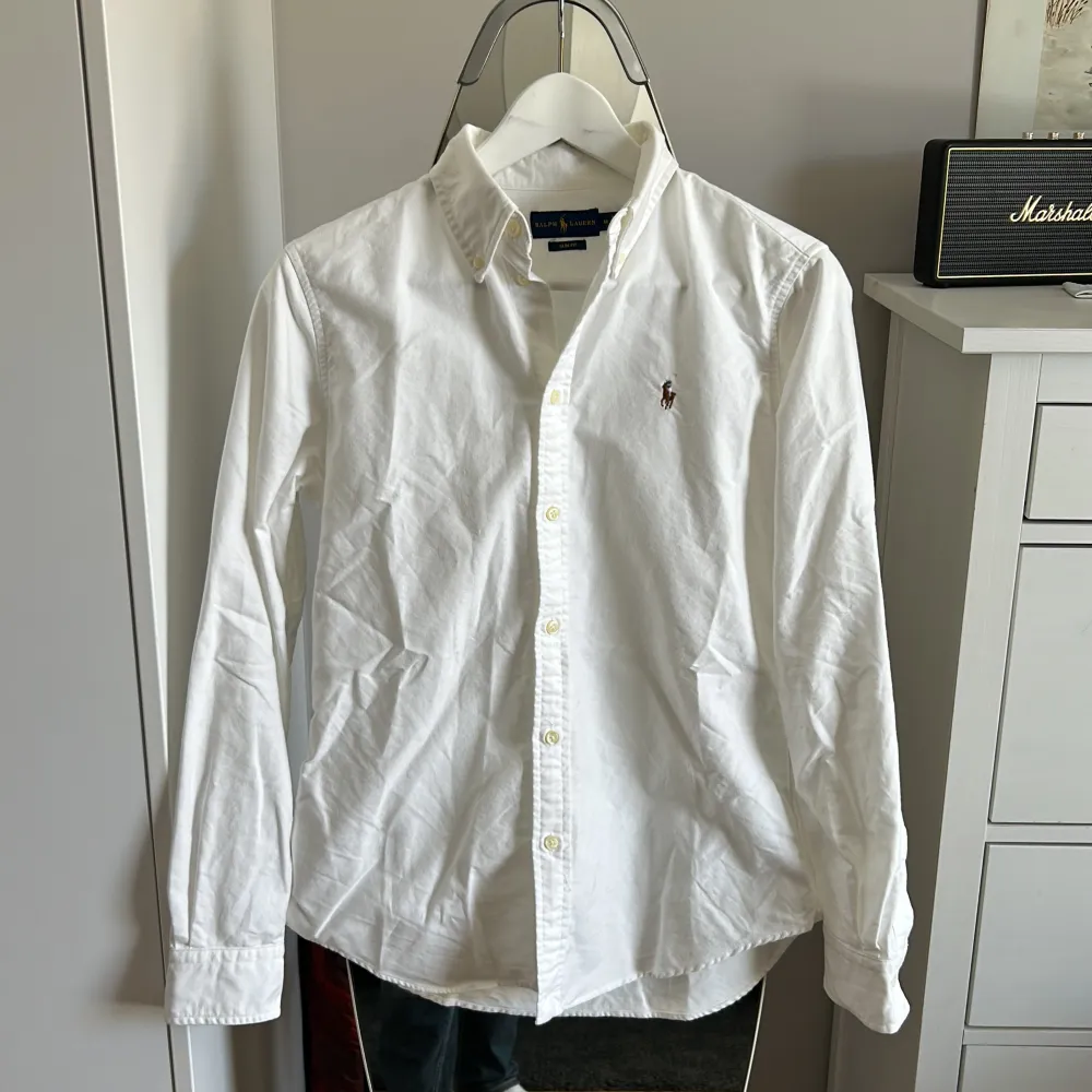 En vit Polo Ralph Lauren skjorta i felfritt skick! Storlek slim fit M passar dock mer som en slim fit S. Nypris runt 1700kr, säljes då den ej kommer till användning.. Skjortor.