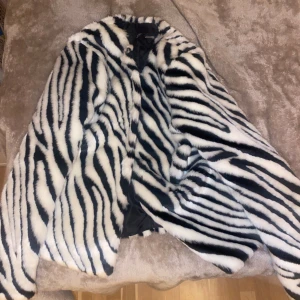Zebra Pälsjacka - Superfin pälsjacka med zebramönster! Den är i princip i nyskick och har liksom små ”hakar” man kan knäppa den med.  Säljer då den kommer till användning för sällan.  Skriv för fler bilder och bilder hur den sitter på. Tryck gärna på köp nu!💕